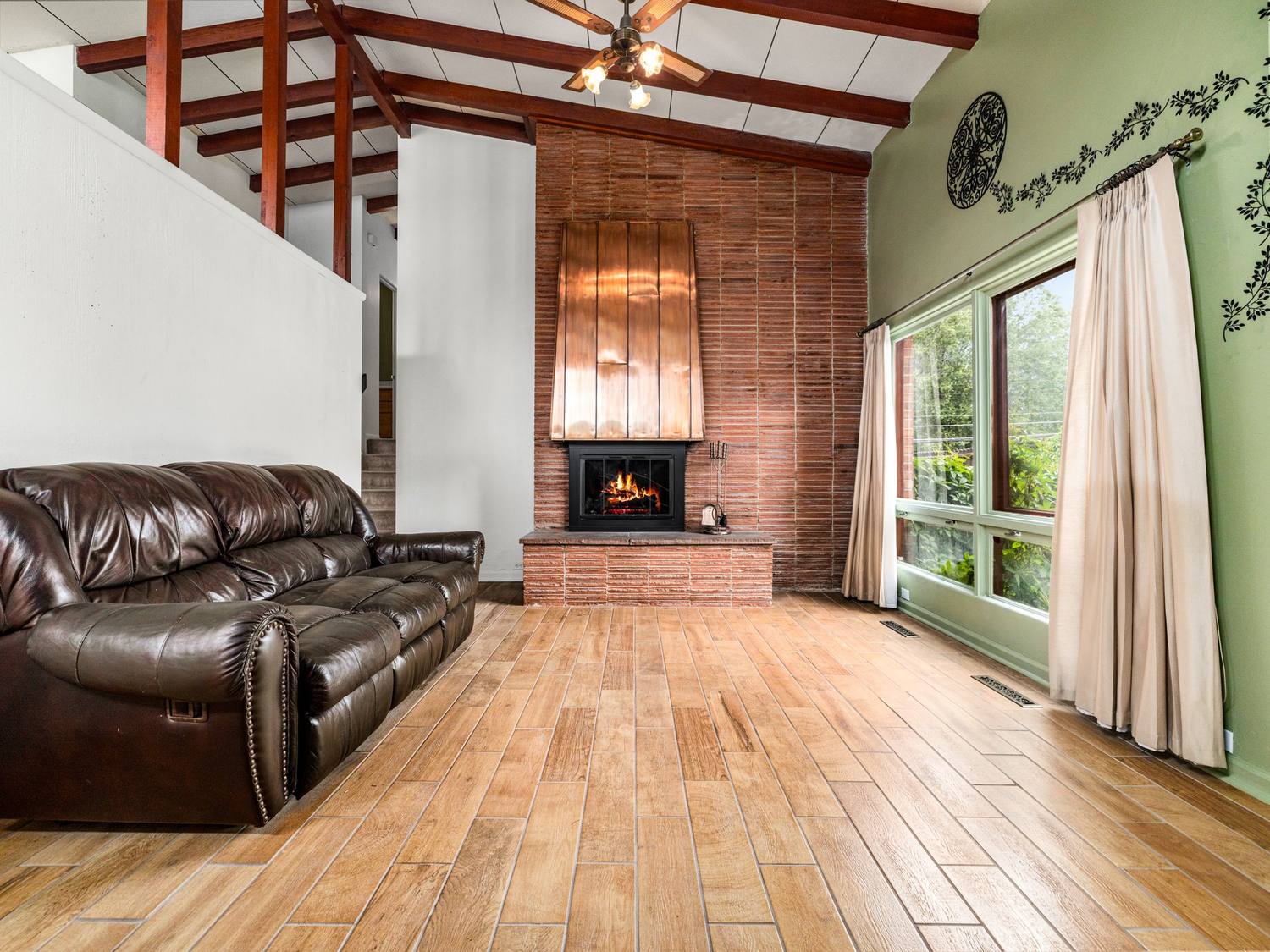 Great room with exposed red roof beams and a copper fireplace hood