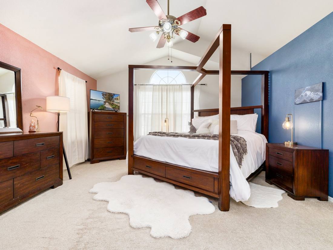 Primary bedroom with a canopy bed under a vaulted ceiling