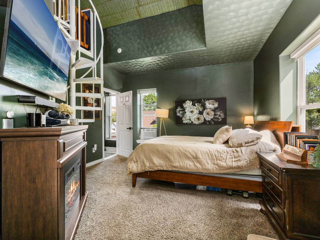Bedroom with green walls, a fireplace and a spiral staircase