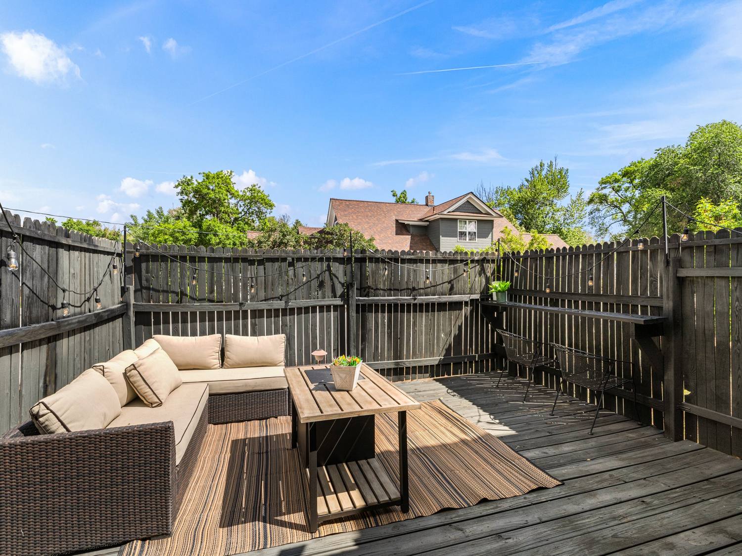 Fenced back deck with sectional seating and string lights