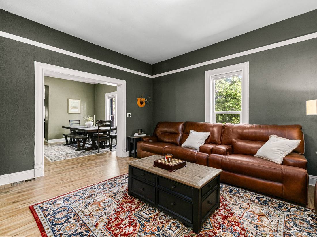 Living room with deep green walls opening to the dining room