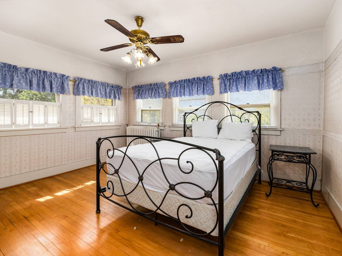 Corner bedroom wrapped in windows with original wood floors