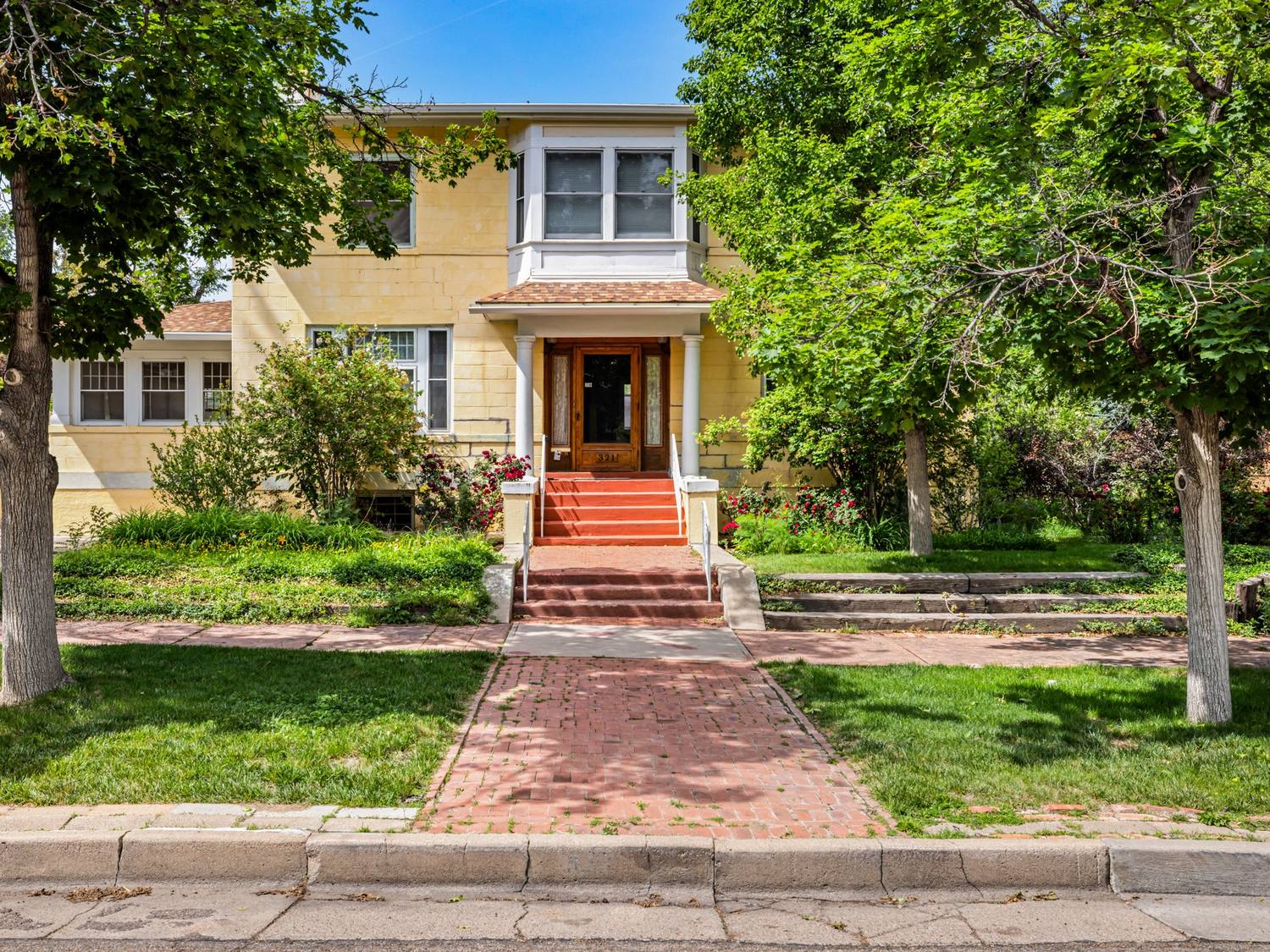 Yellow brick two-story with a bay window and covered porch in Pueblo