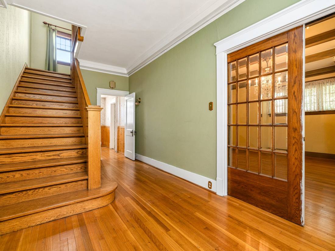 Original oak staircase beside leaded glass French doors